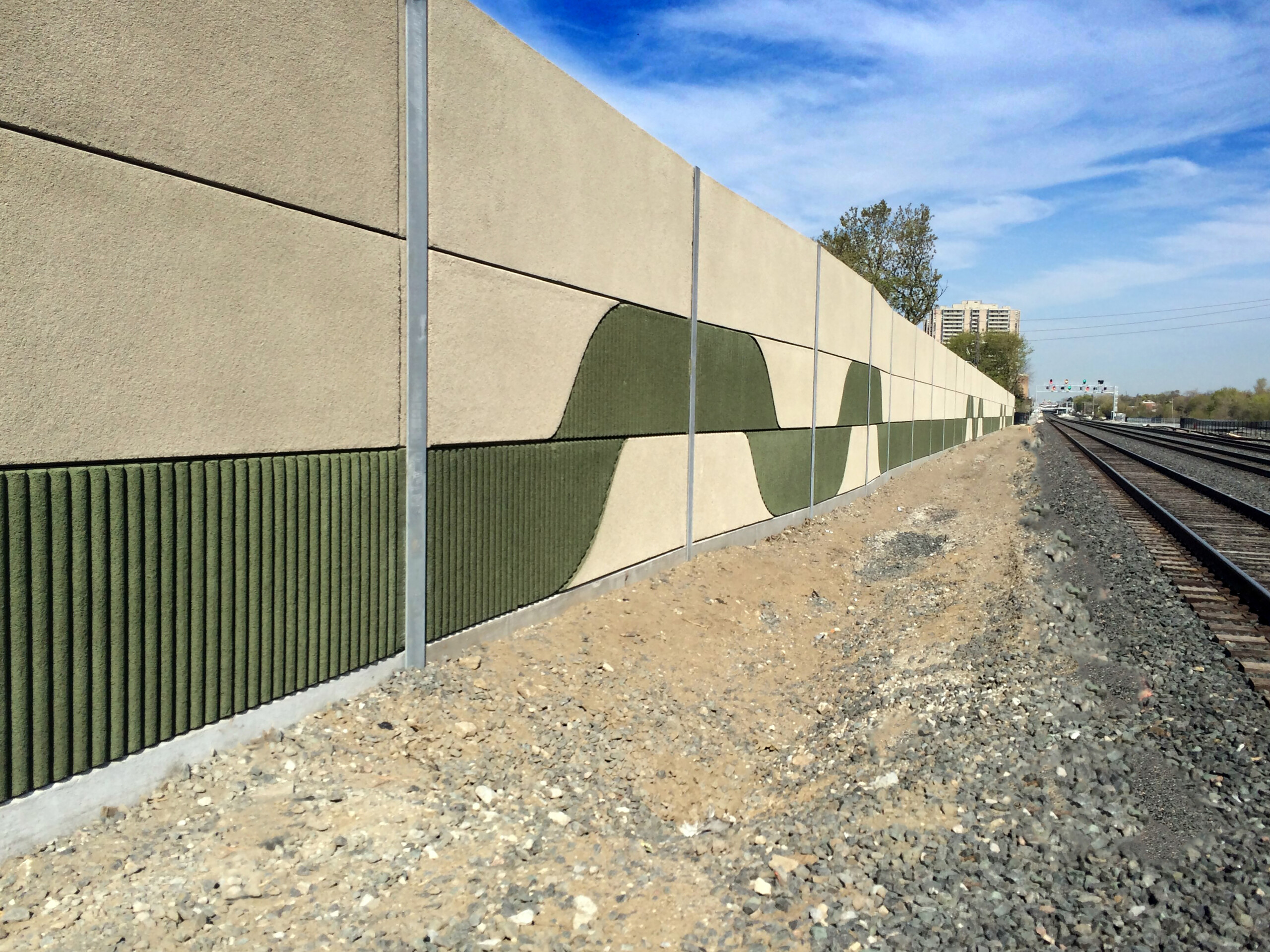 Noise barrier panels featuring a custom "ribbon" pattern in green along Metrolinx's Union Pearson Express rail line in Toronto, ON.