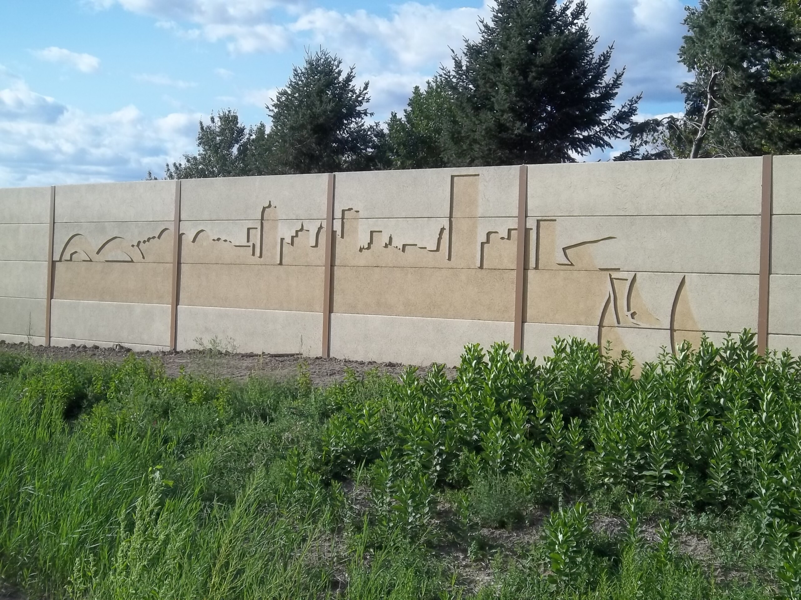 A precast noise barrier featuring a custom cityscape mural along I-94 in Milwaukee, WI.